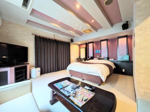大村市SKY Ocean-terace Omura的一间卧室配有一张床、一台电视和一张桌子