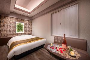 东京Hotel Plantan - Adult Only的一间卧室配有一张床和一张桌子及一瓶葡萄酒
