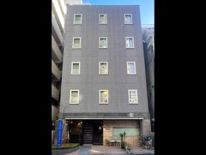 东京WEB Hotel Tokyo Asakusabashi - Vacation STAY 13758v的大街上高大的灰色建筑,窗户