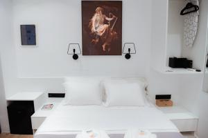 雅典Athens Muses Suites的卧室配有白色的床和墙上的绘画作品