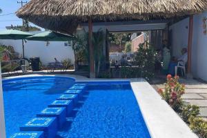 El DesengañoCasa AbrahamMya Playa Linda 3 bed home with pool.的一个带椅子和草伞的游泳池