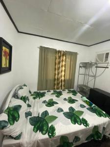 莫阿尔博阿Panagsama Holiday Cottage的一间卧室配有一张带绿色和白色棉被的床