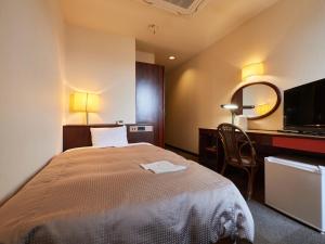 富士市Tabist Hotel New Central的一间卧室配有一张床、一张书桌和一面镜子