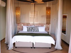 KhorixasLodge Damaraland的一间卧室配有白色窗帘的床