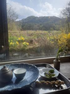 青森Tanehachi Farm Guesthouse - Vacation STAY 29709v的一张桌子,上面有盘子的食物,放在窗边