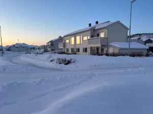 特罗姆瑟Room in Tromsø, Kvaløya的雪中的房子,前面有一条路