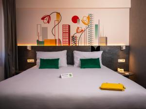 皮特什蒂ibis Styles Pitesti Arges的卧室配有带绿色枕头的大型白色床