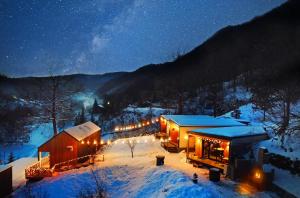 斯兰默多瓦Kub House Village的夜晚雪中被灯光覆盖的房子
