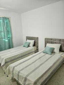 迈来亚App 2 chambres piscine privative 600m plage的两张睡床彼此相邻,位于一个房间里