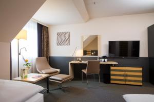 美因河畔法兰克福Lindner Hotel Frankfurt Hochst, part of JdV by Hyatt的酒店客房配有书桌和床。