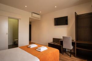 科英布拉河畔套房酒店的一间卧室配有一张床、一张书桌和一台电视