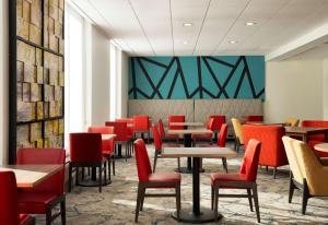 伯灵顿波士顿伯灵顿希尔顿花园酒店的用餐室配有桌子和红色椅子