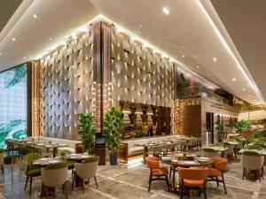伊斯坦布尔Mövenpick Hotel Istanbul Bosphorus的餐厅设有桌椅和葡萄酒瓶壁