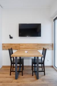 维尔纽斯TopFloor Apartments的一张木桌,配有两把椅子和墙上的一台电视
