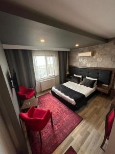阿克恰阿巴德New Akçaabat Hotel的一间卧室配有一张床和两张红色椅子