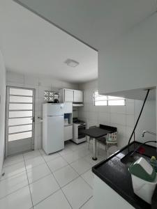 卡鲁阿鲁Nox Temporada - Casa com Piscina e Churrasqueira的白色的厨房配有冰箱和桌子