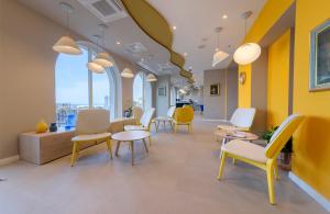 图彻皮Bluesun Hotel Jadran的一间设有黄色和白色椅子和桌子的等候室