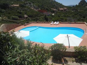 帕拉迪索海岸Villini Cala del Sole - INFINITYHOLIDAYS的一个带两把白色遮阳伞和椅子的游泳池