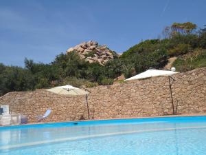 帕拉迪索海岸Villini Cala del Sole - INFINITYHOLIDAYS的一座带遮阳伞的游泳池,毗邻石墙