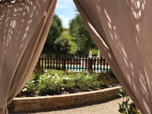 甘巴西泰尔梅Podere Boscone的透过围栏的窗帘可欣赏到花园景色