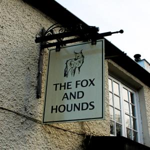 巴里Fox And Hounds Llancarfan的挂在建筑物上的狐狸和猎犬的标志