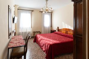 威尼斯蒂沃利酒店的一间卧室配有红色的床、一张桌子和一个窗户。