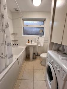 卢顿Visit Luton With This 2 BR Rental - Sleeps 6的带浴缸水槽和洗衣机的浴室