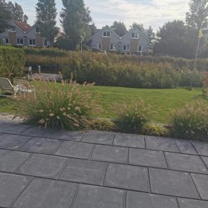 玛库姆Prachtige vakantievilla aan IJsselmeer Makkum的花园,带草坪和房屋的背景