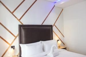 温特和克Deluxe Residence - Windhoek的卧室配有黑色床头板和白色枕头。