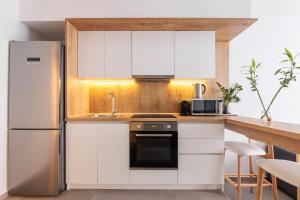 塞萨洛尼基SKG Cityscape Metropolis的厨房配有白色橱柜和不锈钢冰箱