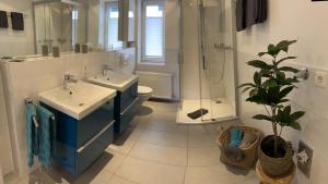 锡默拉特Kragemann Hotel & Vinothek的浴室设有两个盥洗盆、淋浴和植物