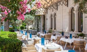 科尔丘拉Aminess Korcula Heritage Hotel的一间带桌椅和粉红色鲜花的餐厅