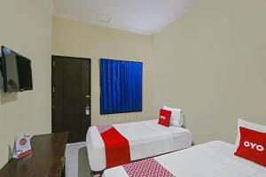 北加浪岸Super OYO 92437 Wahidin Guesthouse的一间酒店客房,设有两张床和电视