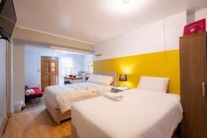 阿亚库乔Casa Samaykuy的酒店客房设有两张床和黄色的墙壁