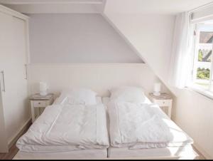 诺尔多夫Ual Öömrang Wiartshüs的卧室内的白色床、白色床单和枕头
