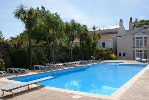Saint Peter Port农庄酒店的一个带椅子的游泳池以及一座房子