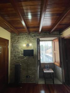 圣地亚哥－德孔波斯特拉Casa de Costoia的一间设有石墙、电视和桌子的房间