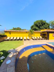 圣菲德安蒂奥基亚Nueva Granada Hotel Colonial -Centro Histórico-的一座带椅子的游泳池以及一座黄色的房子