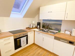 埃姆登datKrughuus的厨房配有白色橱柜、水槽和窗户。