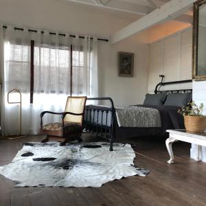 普利登堡湾Urban Plett的一间卧室配有一张床、一把椅子和地毯