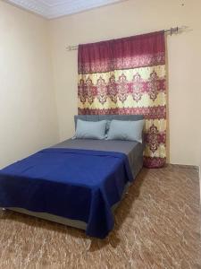 BrikamaIzzy Guest House的一间卧室配有一张带窗帘的蓝色床