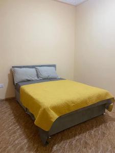 BrikamaIzzy Guest House的一间卧室配有一张黄色毯子床