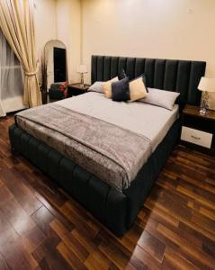 伊斯兰堡LMY Elysium Designer Luxury Apartments Facing Centaurs Mall Islamabad的卧室内的一张大床和黑色床头板