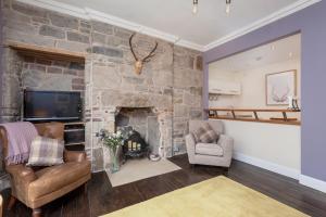爱丁堡玫瑰公寓的客厅设有石制壁炉和两把椅子