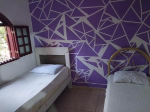 坎普斯戈伊塔卡济斯Guarus house plaza shopping的紫色墙壁客房的两张床