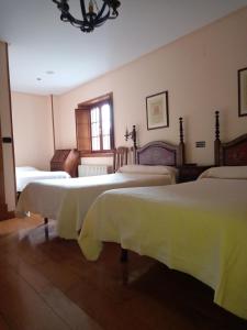 Noceda松鸡酒店的一间卧室配有三张床和白色的毯子