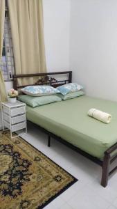 Homestay Seri Aman Pasir Puteh的一间卧室配有一张带绿色床罩和地毯的床。