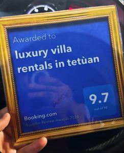 得土安luxury villa rentals in tetùan的持有标志的人,上面写着被授予豪华别墅出租的标志