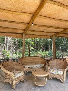 皮雷诺波利斯Sítio Quinta da Mata Chalé Amarelo的木屋顶下有三把柳条椅和桌子