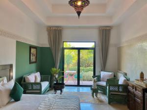 马拉喀什La Villa Des Golfs & PinkCactus的一间卧室配有床和椅子以及大窗户